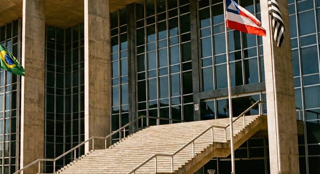 Fachada de prédio de tribunal no Brasil com bandeiras ao vento.