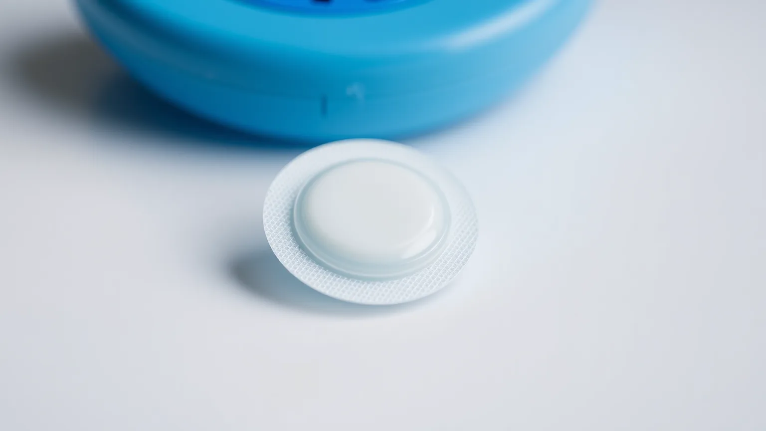 sensor de glicose e seu aplicador sobre superfície branca, ilustrando o dispositivo classificado como produto para saúde